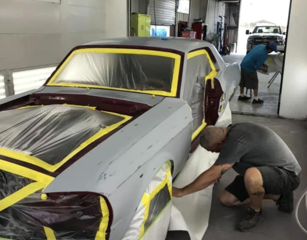 Car masked for paint while a technician preps the lower panel in the Star Auto Body paint shop
